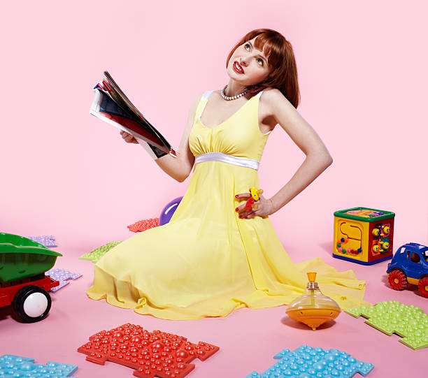 portrait of redhead woman reading magazine and speaking on phone with various toys around