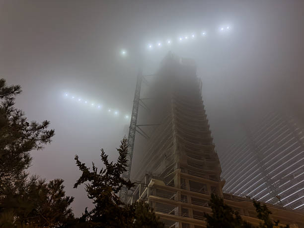 Illuminated Unfinished Skyscraper Construction in Heavy Night Fog