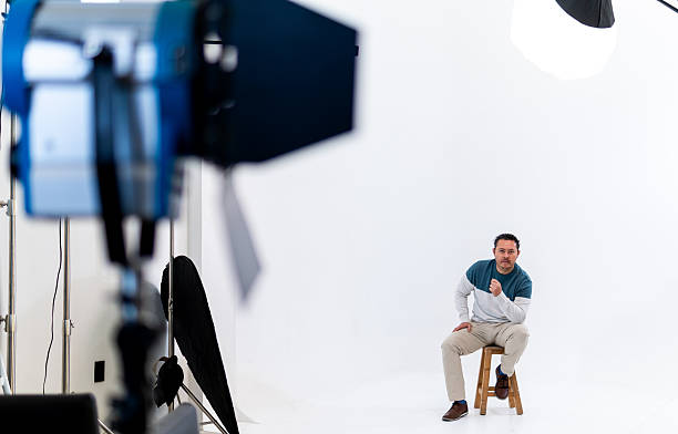 Professional man posing on stool in a photography studio with a white background