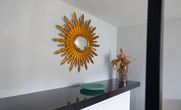 Gold Sunburst Mirror on White Wall with Blurred Dried Flower