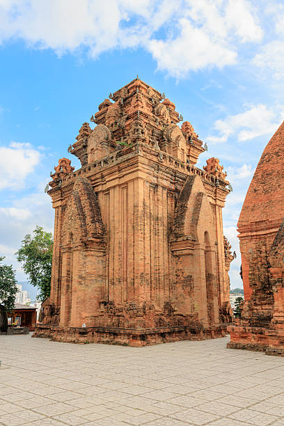 Wide vertical view of the main brick tower of Po Nagar Cham Towers temple complex with open courtyard and bright blue sky in Nha Trang Vietnam