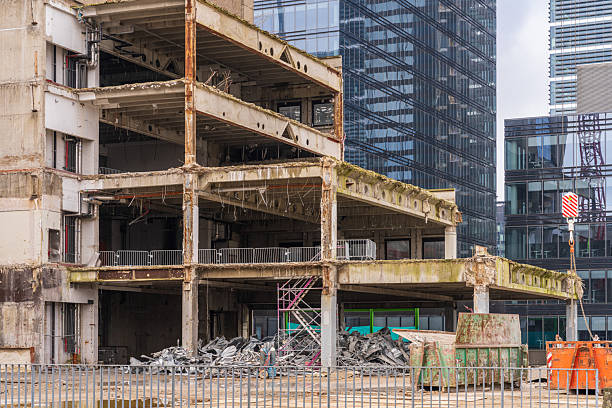 Brussels, Belgium - March 18, 2024: Partially demolished office building with exposed concrete floors, debris, and construction containers during large-scale urban redevelopment