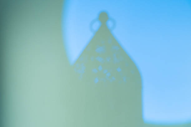 Islamic Lantern Shadow on Green,Blue Wall Background.Ramadan Kareem background lantern silhouette soft lighting for Eid Mubarak greeting card backdrop with traditional fanous shadow,light on two tone