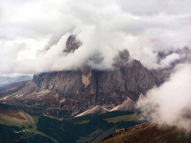 Steep Langkofel mountain peaks in the Italian Dolomites with dramatic clouds surrounding them. Photographed in medium format.