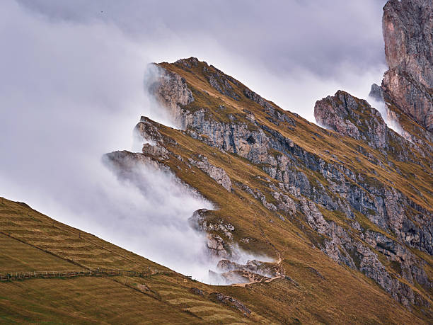 Rocky Seceda mountain landscape with mist moving across sharp peaks at Italina Dolomites. Photographed in medium format.