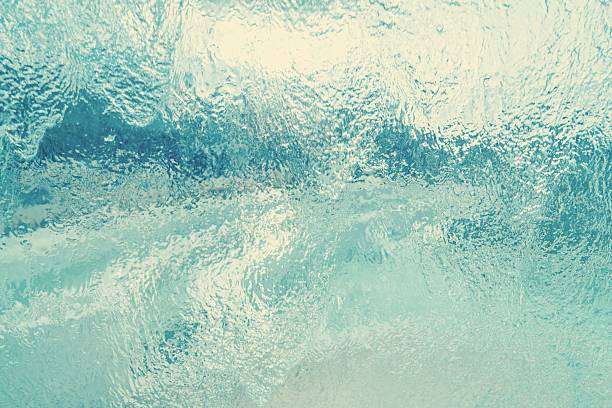 close-up dynamic texture of water flowing down a transparent surface glass panel. Use as a background, texture overlay, or for themes related to freshness, cleanliness, nature, and tranquility.