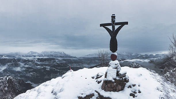 A cross peaks at a mountain with snow