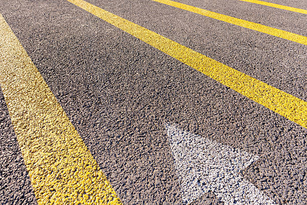 Arrow symbol on asphalt road background.