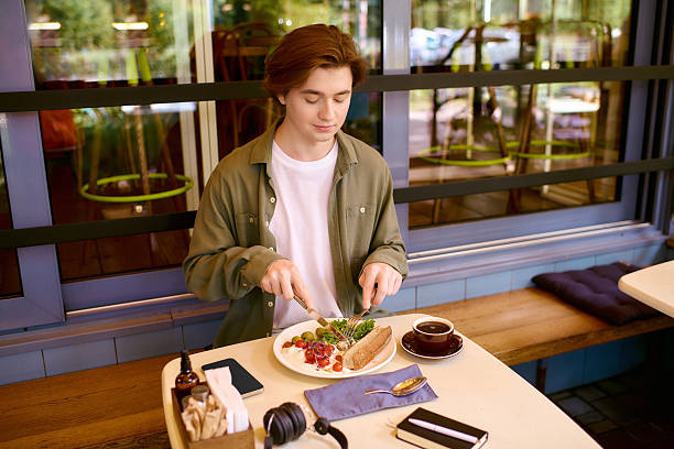 In a chic cafe, a young man in an olive shirt enjoys his delicious meal