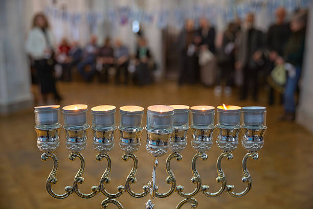 Lit menorah candles creating a warm glow during a Hanukkah celebration with people gathered