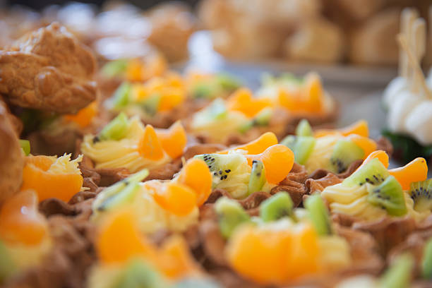 Mini fruit tarts filled with custard, kiwi, and mandarins on a catering buffet