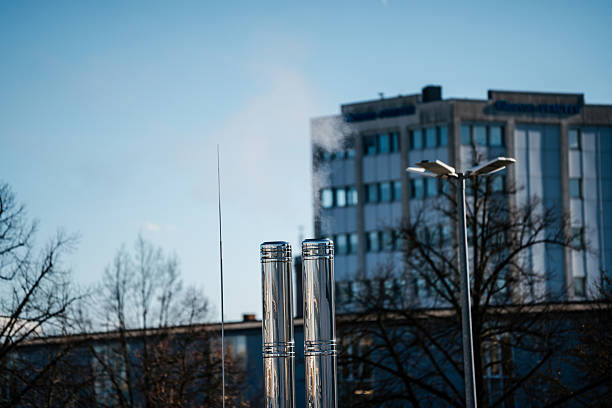 Stainless steel chimneys releasing steam from an urban heating or ventilation system under clear sky.