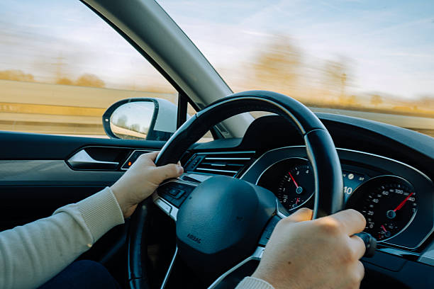 Perspective from inside a car showing steering wheel and motion-blurred landscape outside, symbolizing travel, transportation, and movement.