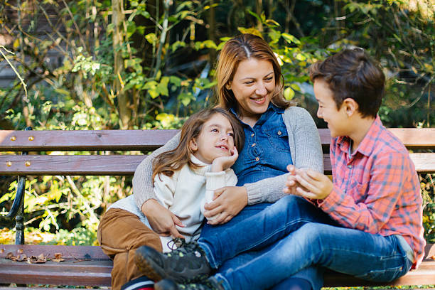 Three generations of women huddle in closely together as they pose for a portrait.  The grandmother, mother and daughter are all dressed casually and smiling.