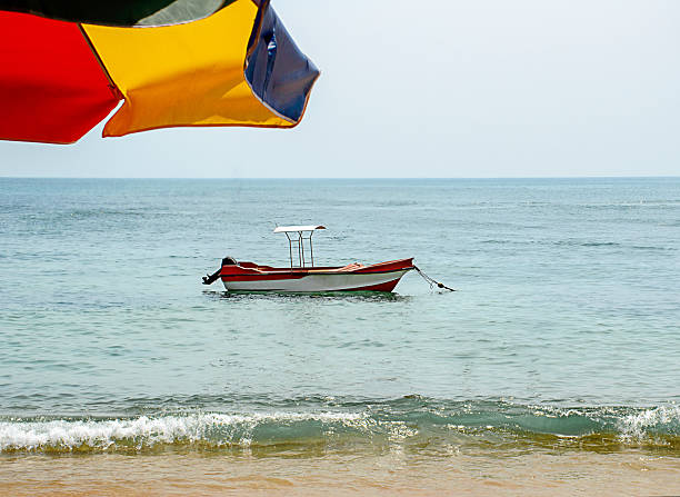 Single small boat anchored on calm ocean water near the beach, with soft waves and open horizon. Clean composition with copy space, symbolizing freedom, travel, solitude, summer vacation, and relaxation. Ideal for tourism, lifestyle, mindfulness, and coastal background concepts.
