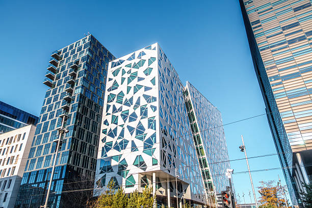 Wide architectural view of modern office and residential buildings in the Barcode district of Oslo, featuring contemporary glass facades, geometric patterns and high rise towers under a clear blue sky, representing modern urban development, business, finance and Scandinavian city architecture in Oslo, Norway