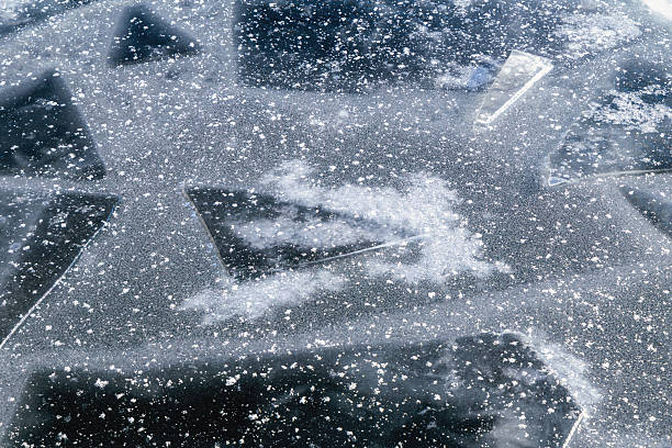 Oslo, Norway - Winter: Close-up view of fractured ice sheets and delicate frozen textures floating on a partially frozen water surface in Oslo. The image highlights natural winter patterns formed by cold temperatures, with crystalline ice fragments, bubbles and snow particles creating an abstract, textured surface that reflects Scandinavian winter conditions and seasonal cold weather