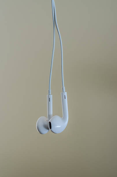 A pair of white wired earphones hanging against a clean, solid color background. Simple concept for personal audio, music, and technology.. High quality photo