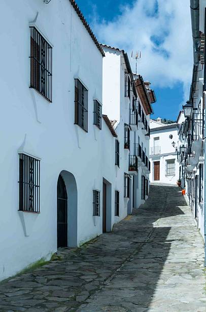 A narrow, cobblestone street with a white building on the left and a white building on the right