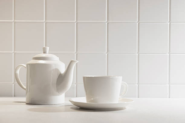 White ceramic teapot, china pot or tea kettle isolated on yellow background