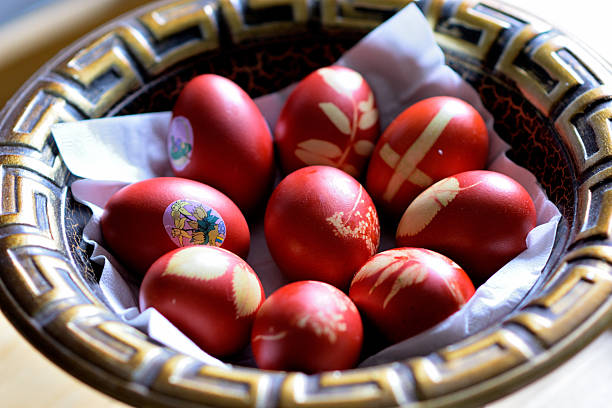 A decorative bowl filled with colorful red Easter eggs adorned with intricate designs