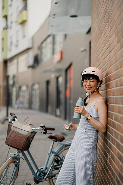 Woman drinking water, resting and standing by bicycle