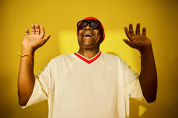 Happy fashion man. Portrait of handsome smiling stylish hipster lambersexual model. Man dressed in yellow sunglasses and black hat. Fashion male on the modern background. Caucasian.