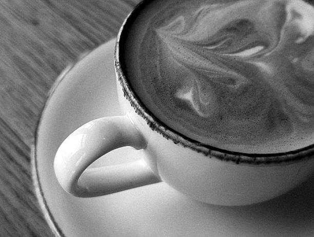 A ceramic cup of black espresso coffee and light bubble with brown stained of coffee water spotted on white backgrounds and copy space, top view angle of shooting image