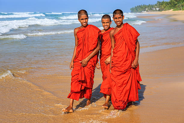 Three Sri Lankan young buddhist monks walking on the beach near Galle, Sri Lanka