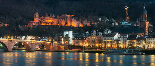 Panorama evening shot of the Old Bridge and the historic Castle in Heidelberg, Germany, reflected on the water of Neckar river