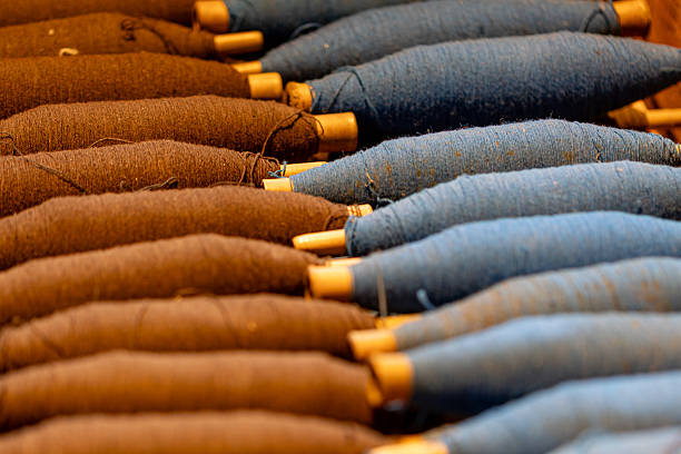 Spools of blue and brown woolen yarn are ready for weaving, representing traditional craftsmanship, textile production, and the intricate process of fabric creation