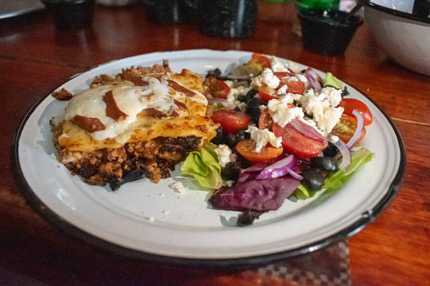 Classic Italian meat lasagna slice with melted cheese and fresh mixed salad