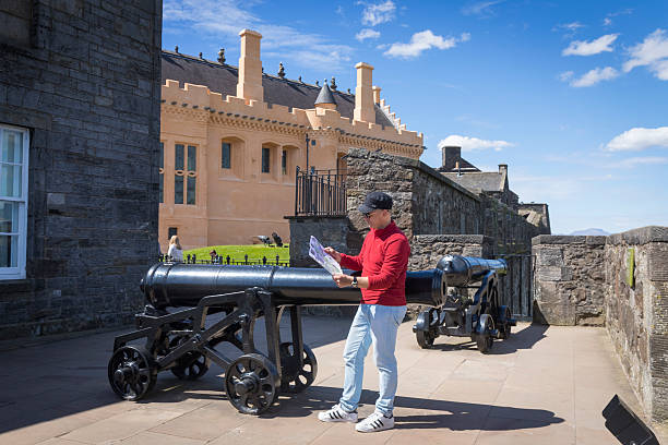 Cannons on the battlements of Stirling Castle, in the part of the outer defenses known as the French Spur. A tourist reads information about this place