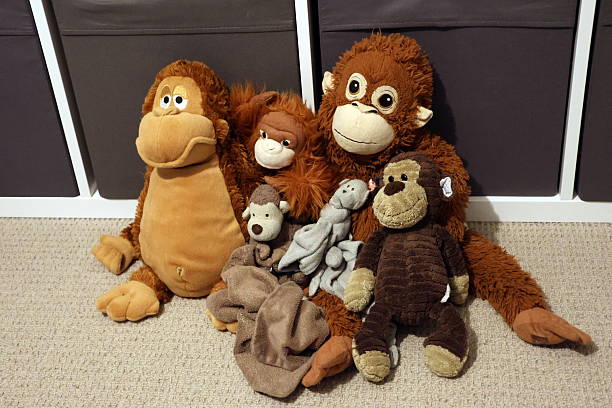 A group of stuffed monkey's are sitting on a carpet. Concept of warmth and comfort, as the stuffed animals are arranged in a cozy manner
