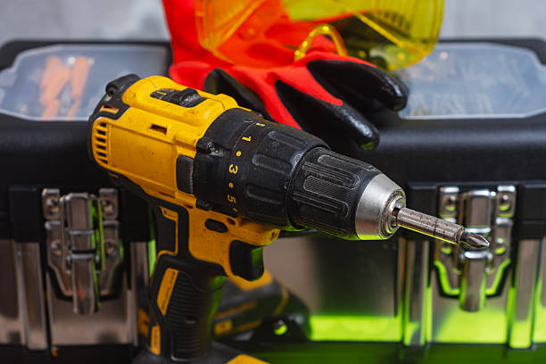 Cordless drill with tool box with protective gloves and safety goggles. Concept of construction work, home improvement, repair service, DIY, professional tools and workplace safety