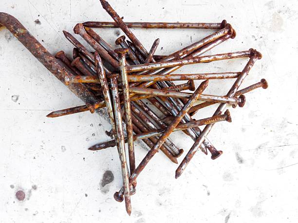 Rusty long nails of different sizes are piled up on a light surface.