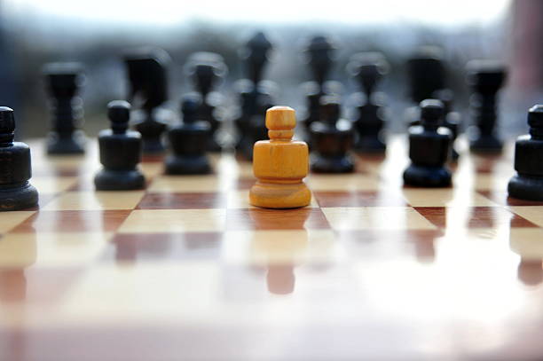 A technical documentary photograph recording the spatial relationship between a single white pawn and a supporting line of black pieces on a traditional wooden chessboard. The image highlights the application of shallow depth of field and natural winter lighting to emphasize a specific component of the game set.