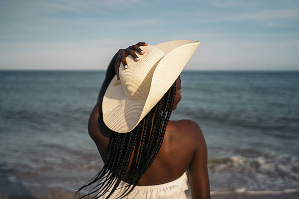 istock Woman enjoying ocean view wearing sun hat on beach 2258346555