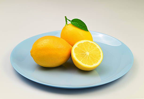 Three lemons are on a blue plate. The plate is on a white background. The oranges and lemon are fresh and ready to eat