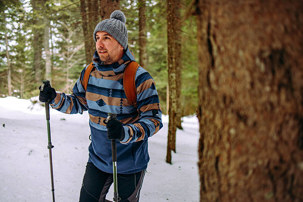 Handsome man hiking through the snowy footpath in the forest