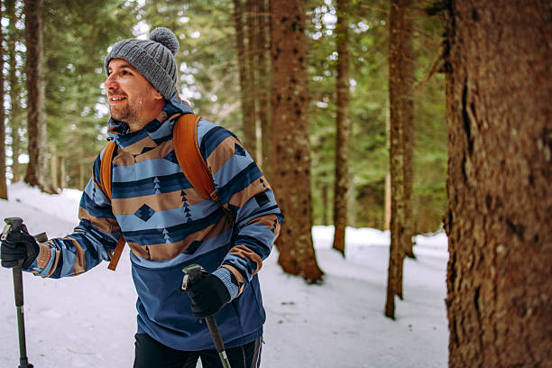 Handsome man hiking through the snowy footpath in the forest
