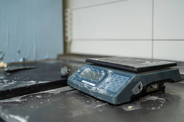 Electronic scale placed on a dark counter in an Italian restaurant kitchen. The scale is covered with flour, indicating its use in food preparation.