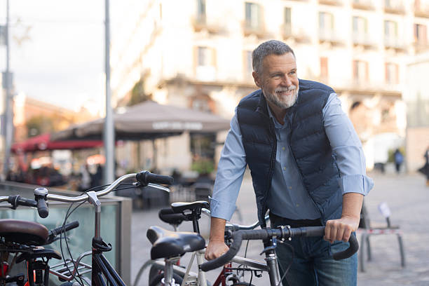 Mature man smiling while parking his bicycle in an urban setting
