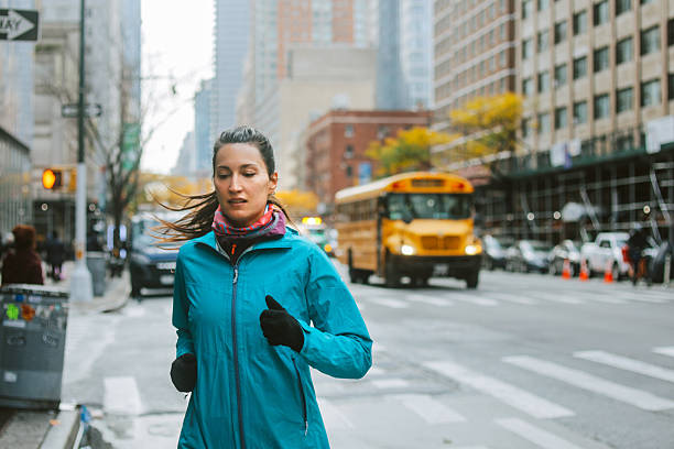 Woman jogging through city streets of Manhattan as part of her daily training routine. Real people, urban fitness and healthy lifestyle captured in a natural, documentary style setting.