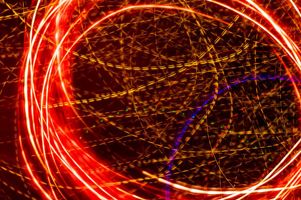 Bright light trails create futuristic patterns against a dark backdrop. Abstract background with defocused lines and curves, made by glowing fiber optic lights.