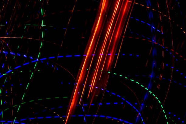 Bright light trails and spots create futuristic patterns against a dark backdrop. Abstract background with glowing curves and spots, made by glowing fiber optic lights.