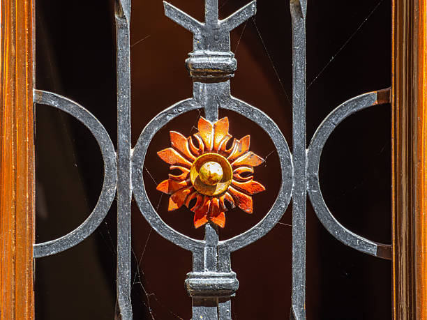 Ornate iron gate in Skofja Loka, Slovenia, with sunburst design and cobwebs.