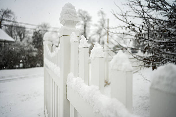 White picket fence posts covered with fresh snow during a winter snowfall in a residential area
