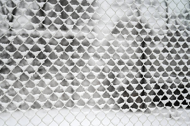 Chain link fence showing intricate pattern of white snow and ice