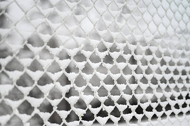 Chain link fence covered in sparkling white snow and ice in a cold winter setting